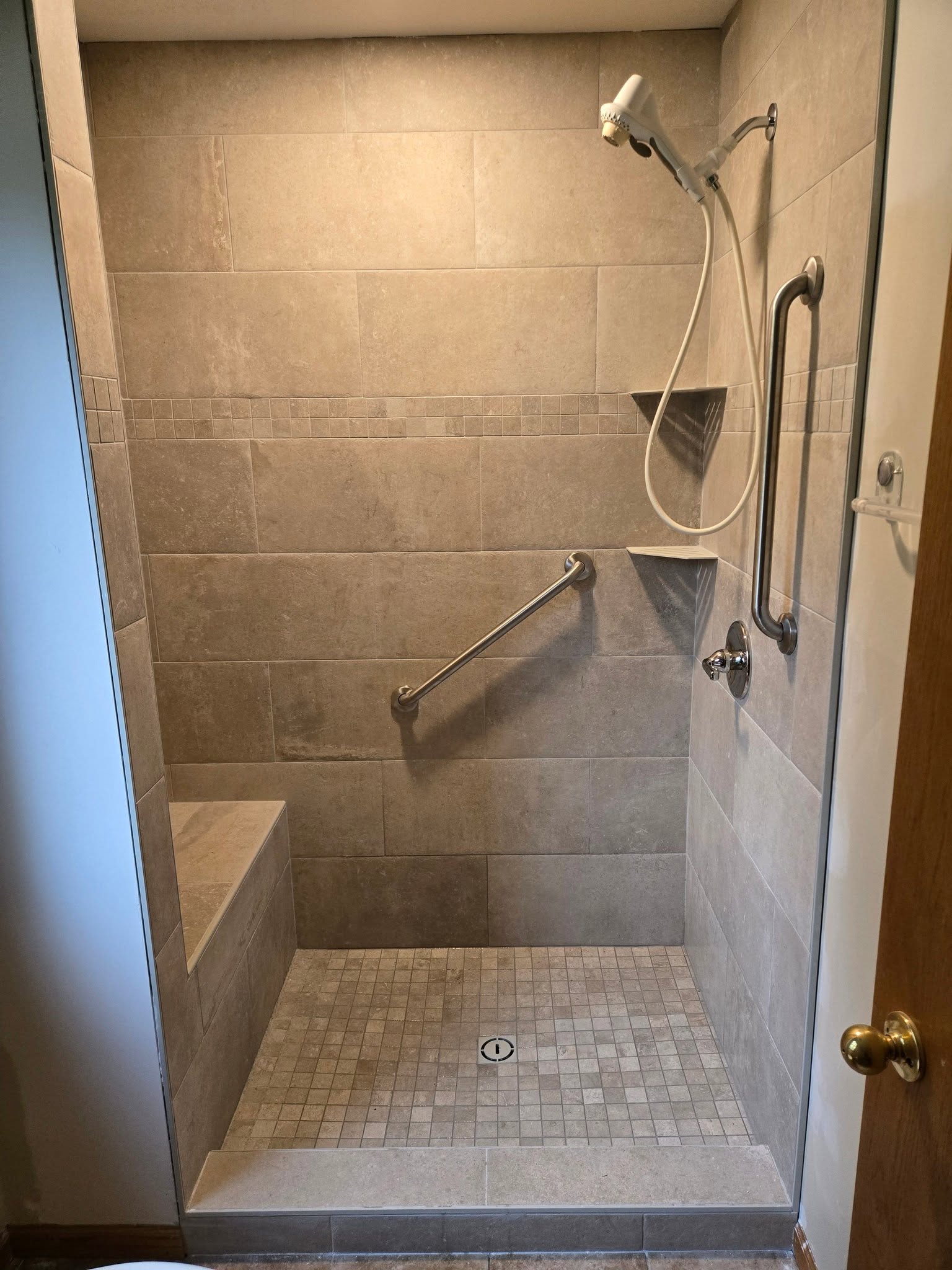 Tiled walk-in shower with grab bars and bench seat