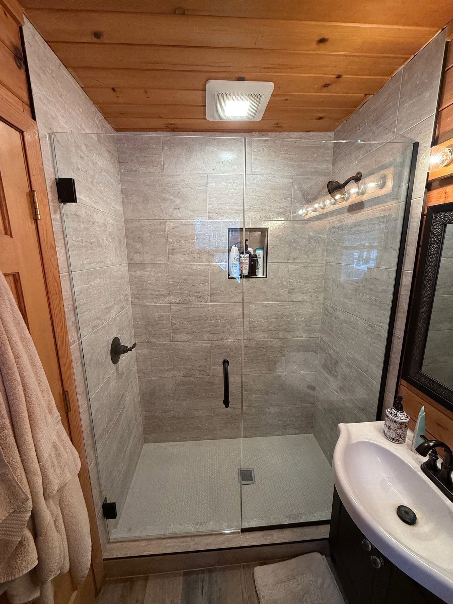 Cabin bathroom glass shower with stone-look tile