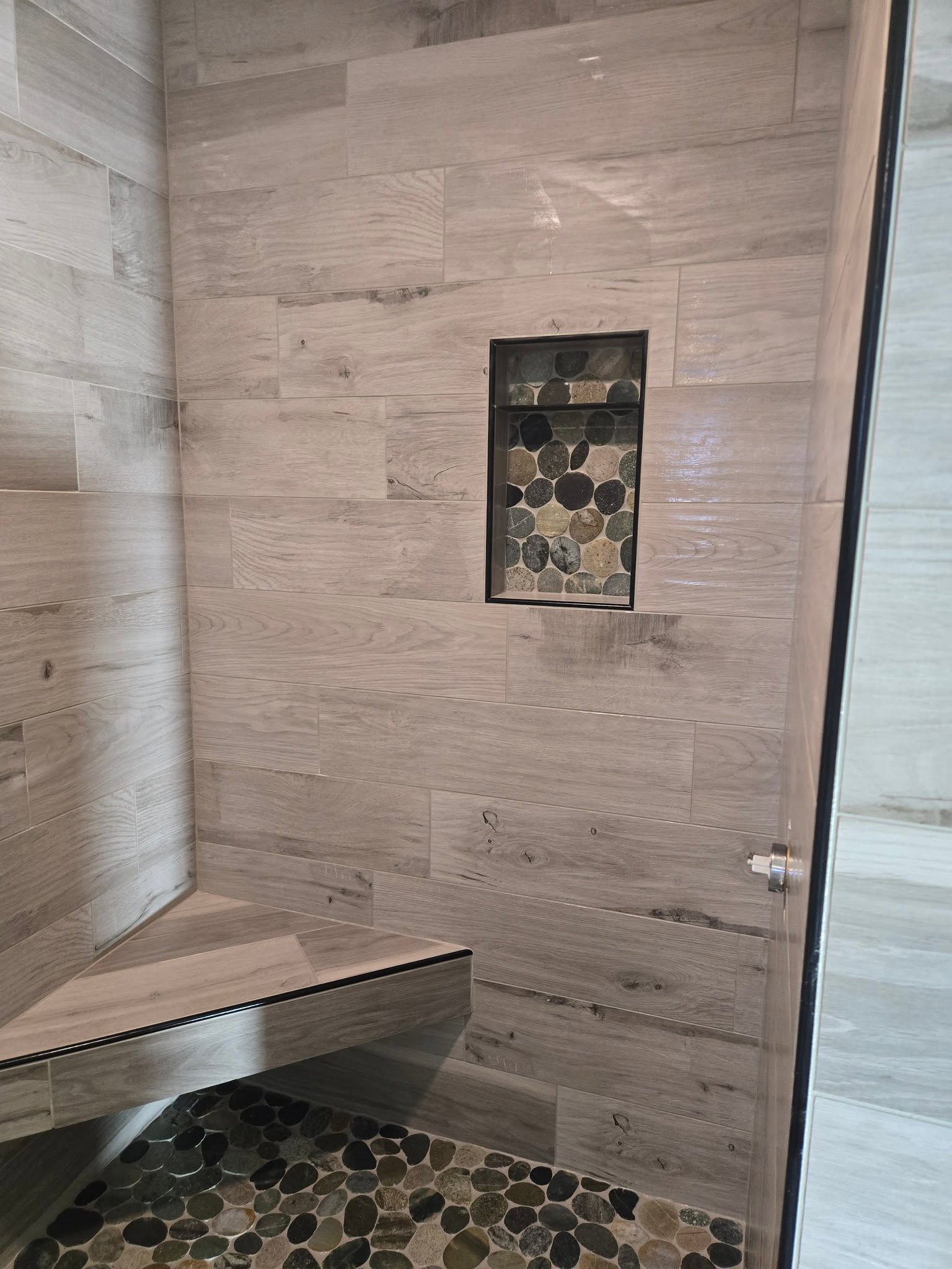 Wood-look plank tile shower with pebble accent niche